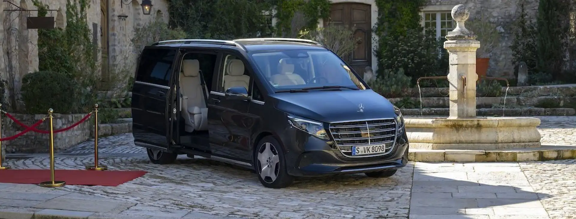 A black Mercedes V-Class in the front view, with a red carpet rolled out in front of it.